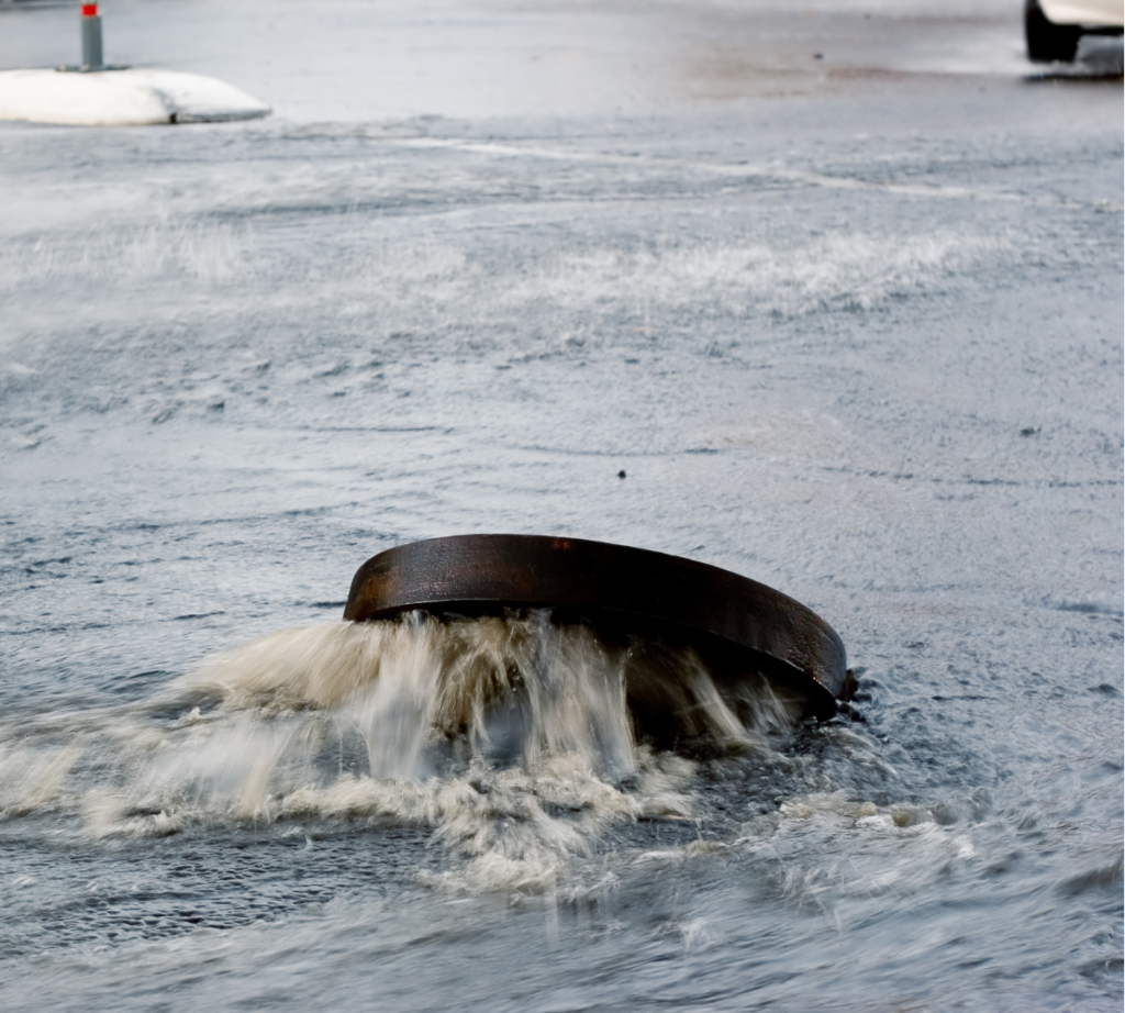 A manhole overflowing in a flooded street