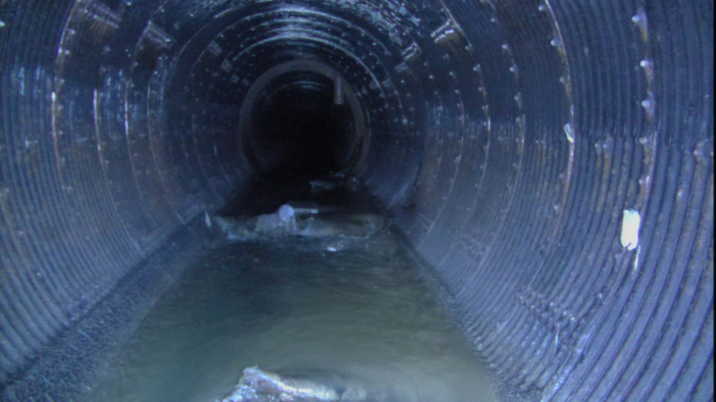 Interior of a large diameter sewer pipe with flow and debris